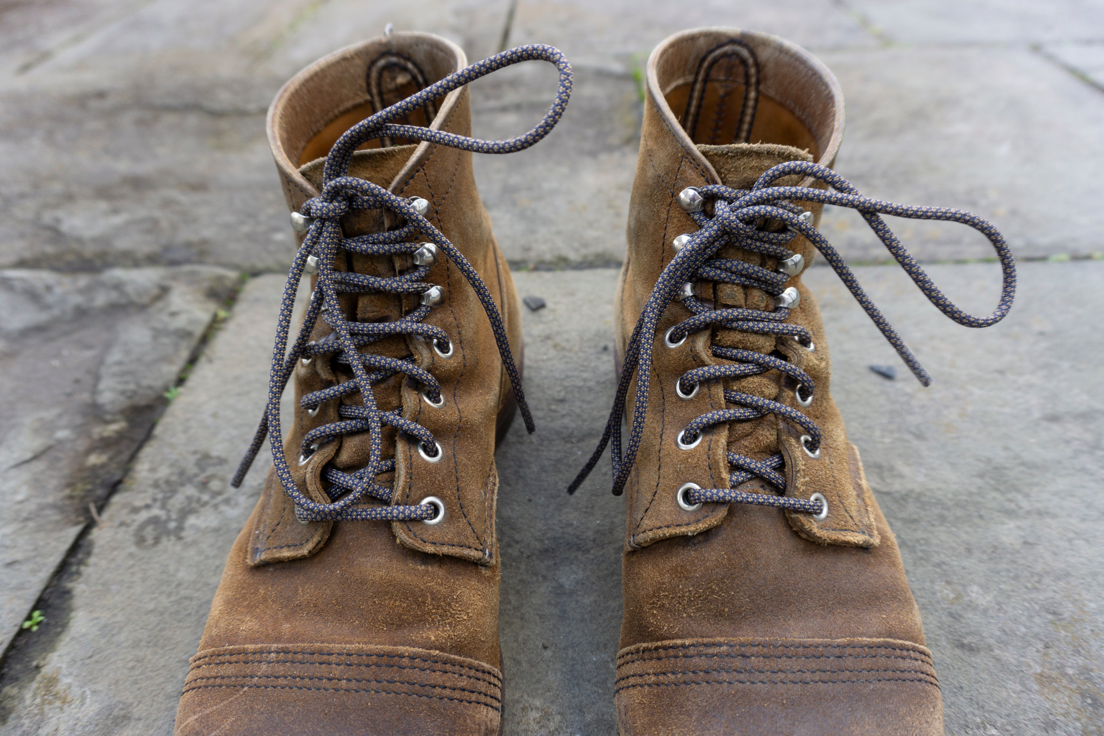 Pair of brown leather boots with laces on a stone surface